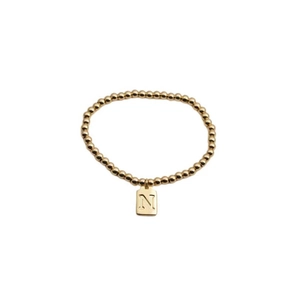 Détail d'un bracelet de perles plaqué or avec un pendentif carré gravé de la lettre N