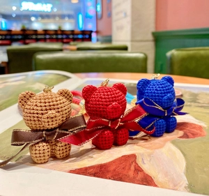 Handcrafted knit-style bear keychains in coffee, red, and blue with gold ribbon accents