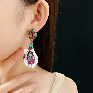 Detail view of model wearing vintage floral drop earrings with red gems and enamel