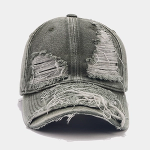 Close-up of distressed washed denim baseball cap with vintage frayed holes and texture