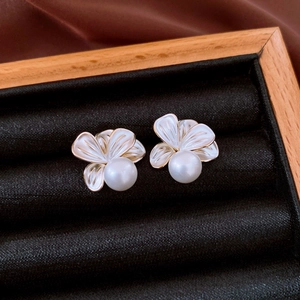 Detail of white flower stud earring with pearl center and 18K gold plated edges