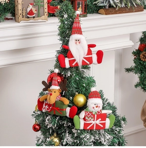 Close-up of plush Santa, reindeer, and snowman ornaments hanging on a snowy Christmas tree