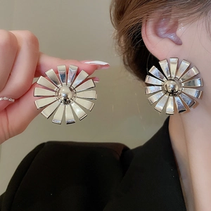 Macro view of silver metallic sunflower earrings showing shiny mirror finish and details
