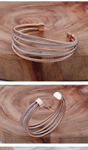 Detailed view of multi-layer twisted cable cuff bracelet in rose gold and silver finish