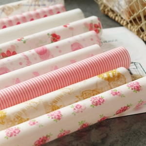 Close-up of greaseproof wax paper rolls with strawberry and floral patterns for baking