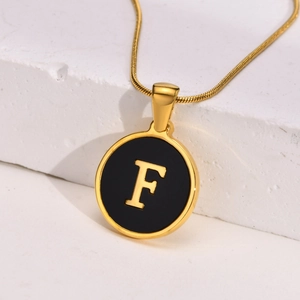 Detail of round 18K gold plated letter F pendant with black enamel finish on chain