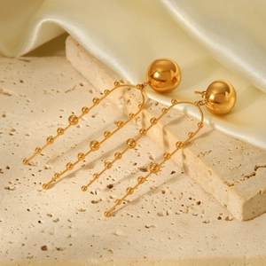 Golden stainless steel spherical stud earrings with elegant beaded tassel on beige stone
