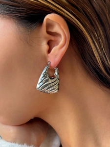 Close-up of silver vintage textured earrings featuring modern ripple hollow design