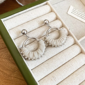 Detail shot of fan-shaped silver earrings with beige pleated leather in a jewelry box