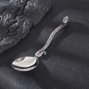 Vintage stainless steel spoon with creative serpent handle design on textured background