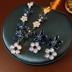 Close-up of luxury flower jewelry set with blue zircons on a black display tray