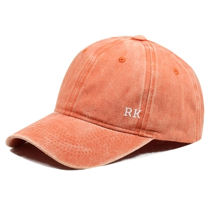 Detailed view of white RK letter embroidery on vintage washed orange cotton baseball cap