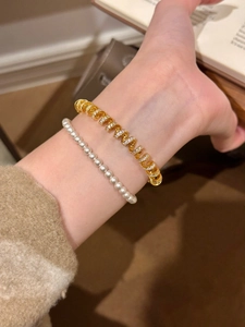 Close-up of 18K gold plated twisted zircon bracelet and pearl bangle on wrist