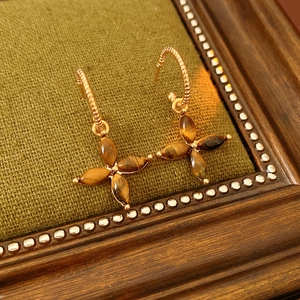 Macro shot of vintage tiger eye clover earrings with gold twisted texture on green backdrop