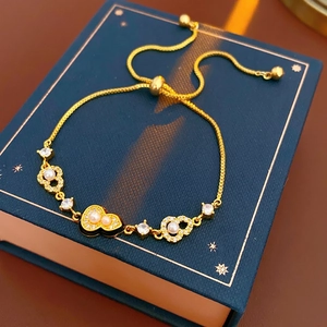 Adjustable gold plated heart bracelet with pearls and crystals on navy blue jewelry box