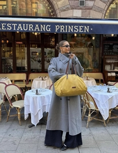 Elegante cappotto lungo in lana abbinato a una grande borsa gialla in stile urbano