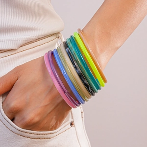 Close-up of a colorful resin bangle set worn on hand with a stylish fabric pocket background