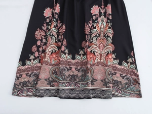 Detailed view of the ethnic floral pattern and hem of the black halter maxi dress