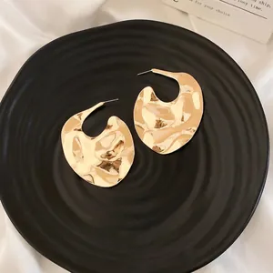 Minimalist gold textured metal hoop earrings with elegant hammered surface design
