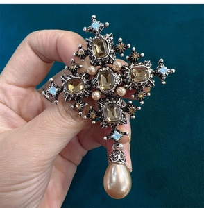 Detail of vintage Baroque cross brooch with amber gems and a large teardrop pearl pendant