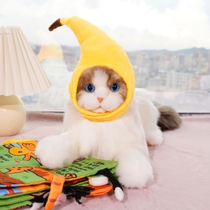 Detail view of a white plush cat wearing a bright yellow banana-shaped pet headgear accessory