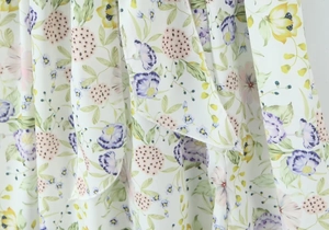 Détail du tissu à imprimé fleuri ivoire avec des fleurs violettes et roses de près