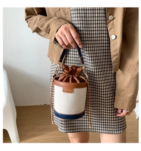 Detail of canvas bucket bag with leather patchwork and drawstring closure on handle