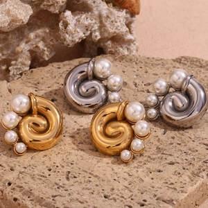Detailed shot of gold and silver spiral twist stud earrings with pearls on rock surface