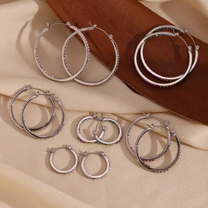 Macro detail of silver hoop earrings with multicolored rhinestones on satin fabric