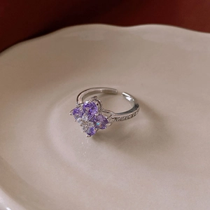 Close-up of four-leaf flower ring with purple zircons on a vintage ceramic plate
