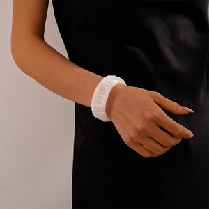 Close-up of a white geometric faceted beaded bracelet on a model wearing a black dress