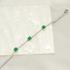 Detailed close-up of emerald and cubic zirconia tennis bracelet with silver-tone chain