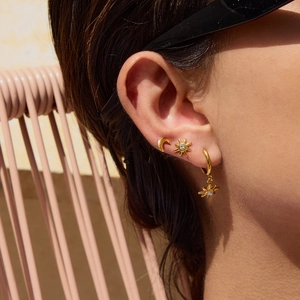 Macro detail of gold celestial earrings with moon and star studs on a model