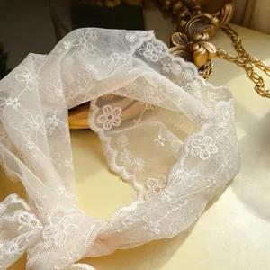 Close-up of white lace triangle hair scarf with delicate floral embroidery detail