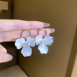 Détail de boucles d'oreilles fleur aux pétales marbrés et pierres de zircon brillantes