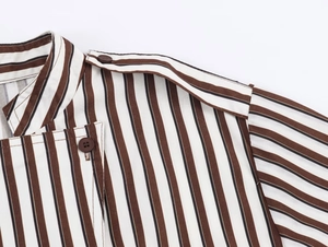 Close-up of brown and white striped shirt featuring epaulette detail and brown button