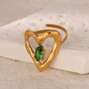 Dettaglio dell'anello a cuore dorato con pietra smeraldo e texture martellata lucida
