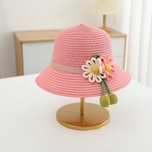 Detailed close-up of pink straw hat with woven flowers and polka dot ribbon on a stand