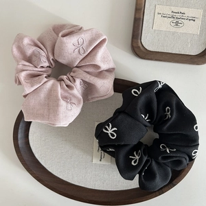 Close-up of pink and black cotton hair scrunchies with elegant bow embroidery details