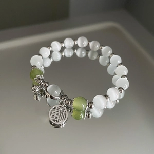 Makrofoto von Opal-Perlenarmband mit Silberglöckchen und Glücksbringer-Fu-Anhänger