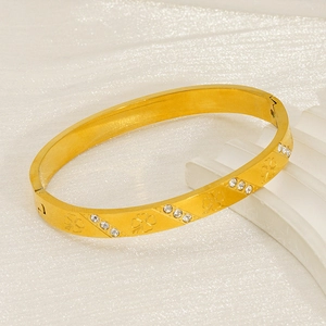 Detail of 18k gold plated bangle featuring clover engravings and inset white crystals