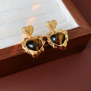 Close-up of gold-plated tiger eye heart earrings displayed in a luxury wooden box