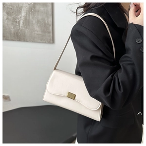 Detail of white vintage underarm bag with gold metal buckle on a black blazer