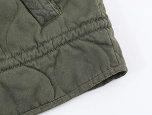 Detailed macro view of diamond quilted stitching on a dark green cotton jacket fabric