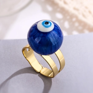 Macro view of adjustable gold-plated evil eye ring with blue enamel bead and polished finish