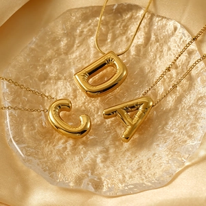 Detailed macro view of golden balloon letter pendants C, D, A on ripple glass and silk