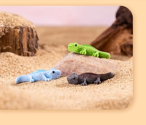 Macro view of realistic resin lizard figurines in green, blue, and brown in a desert setting