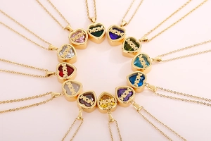 Macro shot of twelve gold heart necklaces with MOM lettering and colorful birthstones