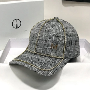 Detail of tweed baseball cap with rhinestones and metal M logo in premium gift box