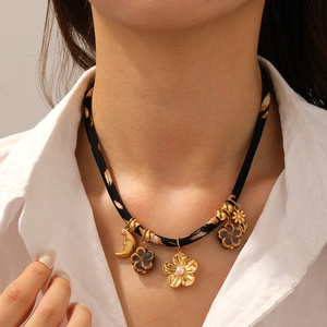 Close-up of a leopard print cord necklace with gold floral and moon pendants on a woman